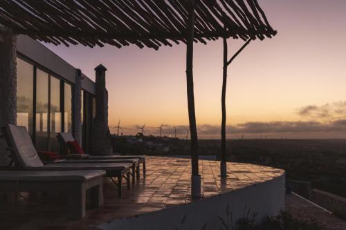 a group of chairs and umbrellas on a patio with the sunset at DAV MAHAL Eco lodge in Sidi Kaouki