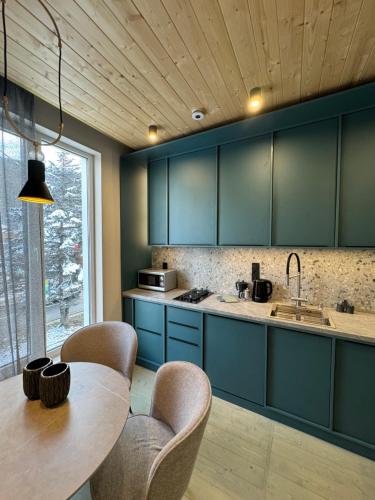 a kitchen with blue cabinets and a wooden ceiling at Girske Povitria Apartments in Yaremche