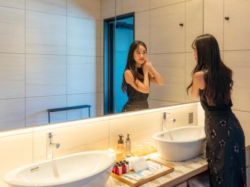 a woman standing in front of a bathroom mirror at FIVE SPRING RESORT THE SHIRAHAMA in Shirahama