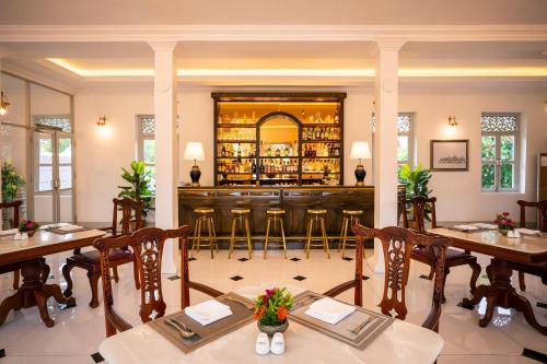 a restaurant with a bar with wooden tables and chairs at Villa Santi Hotel in Luang Prabang