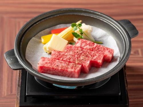 a pan filled with meat and cheese and vegetables at FIVE SPRING RESORT THE SHIRAHAMA in Shirahama