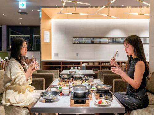 two women sitting at a table in a restaurant using their cell phones at FIVE SPRING RESORT THE SHIRAHAMA in Shirahama