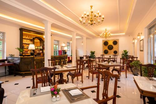 a restaurant with tables and chairs and a chandelier at Villa Santi Hotel in Luang Prabang
