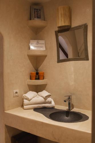a bathroom with a sink and a mirror and towels at DAV MAHAL Eco lodge in Sidi Kaouki