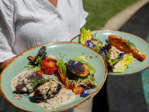 a person holding two plates of food at Blue Karma Dijiwa Seminyak in Seminyak