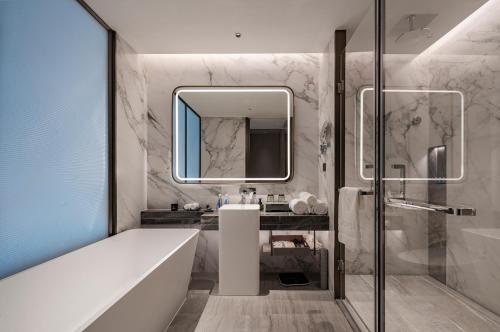 a bathroom with a tub and a sink and a mirror at 开芯国际大酒店 in Guangzhou