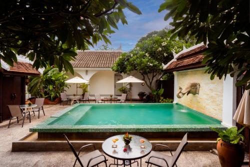 a pool in a courtyard with tables and chairs at Villa Santi Hotel in Luang Prabang