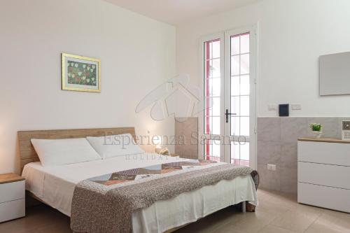 a white bedroom with a large bed and a window at Appartamento Stella Maris in Marina di Mancaversa