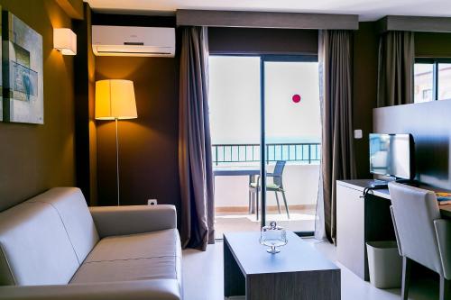 a living room with a couch and a television at Hotel Playas de Torrevieja in Torrevieja