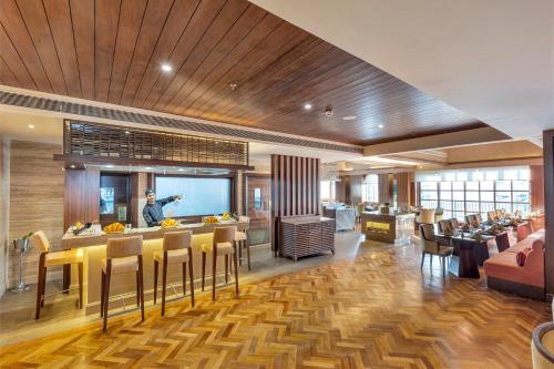 a restaurant with a bar with yellow chairs and a man in the background at Club Mahindra Pristine Peaks Naldehra in Shimla