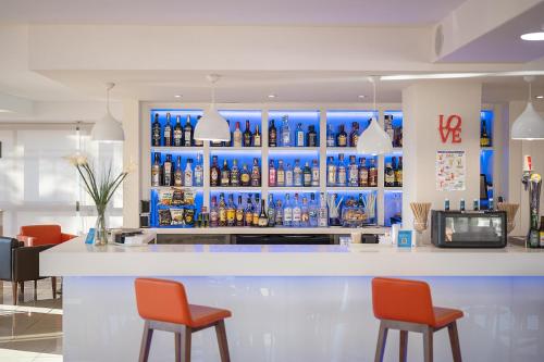 a bar with orange chairs and bottles of alcohol at Hotel Playas de Torrevieja in Torrevieja
