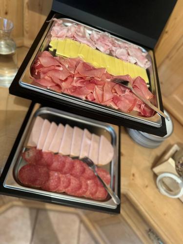 two trays of food with meat and cheese on a table at Residence Garni Stella in San Vigilio Di Marebbe