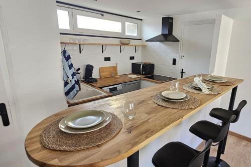 une cuisine avec une table en bois, des assiettes et des verres dans l'établissement Charmant Appartement Refait à Neuf à Nancy, à Nancy