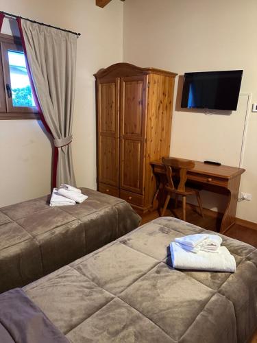 a room with two beds and a desk and a television at La corte dell'ulivo in Polazzo