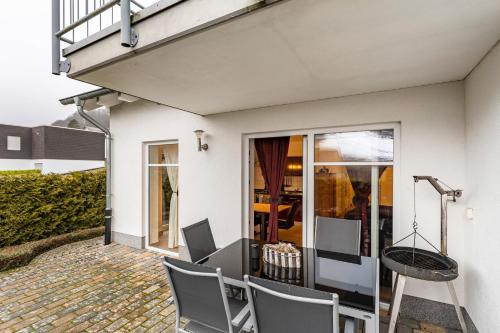 a white house with a table and chairs on a patio at Fewo Zur Piste in Willingen