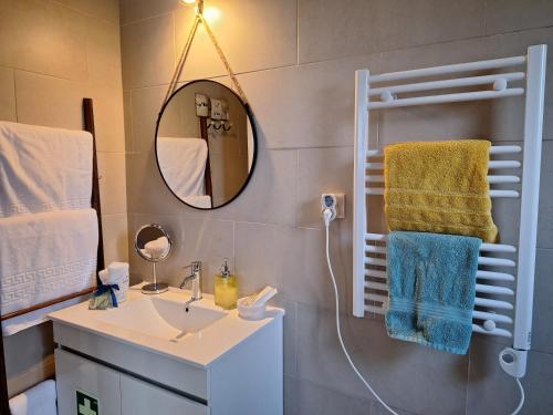a bathroom with a sink and a mirror and towels at Quinta dos Chorões in São Vicente Ferreira