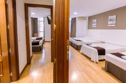a hotel room with three beds and a couch at Hostal Gran Vía in Pinto