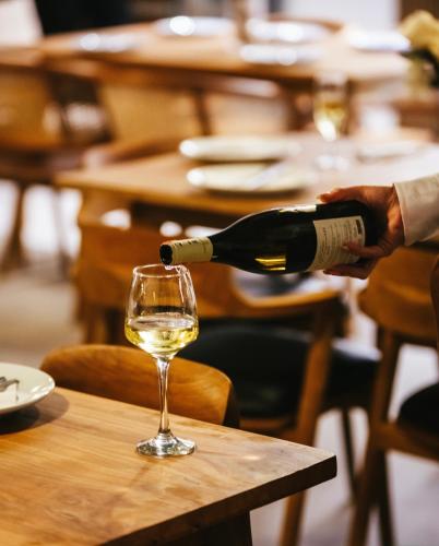 a person pouring a bottle of wine into a glass at Avenue Hotel in Ksamil