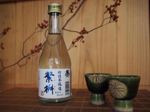 a bottle of wine sitting on a table with two cups at RITA Yame Fukushima in Yame