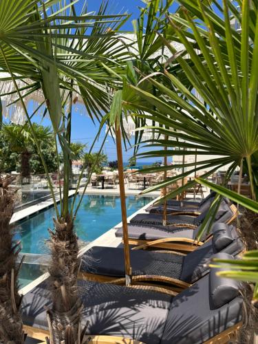 a resort with a pool with chairs and palm trees at Avenue Hotel in Ksamil