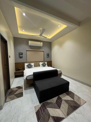 a bedroom with a bed and a black ottoman at Hotel Sundarai Lodging in Jāmkhed