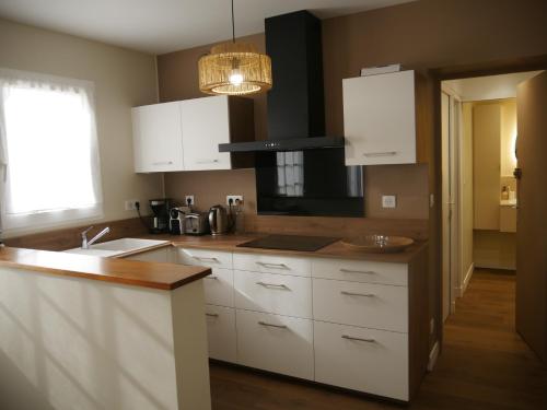 une cuisine avec des armoires blanches et un évier dans l'établissement TY LAOUEN - 1km des plages - Jardin - Wifi -, à Saint-Philibert