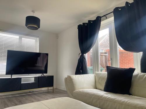 a living room with a couch and a flat screen tv at Modern & Spacious 3-Bedroom Home in Dartford, Ideal for Families, Groups and Contractors in Dartford