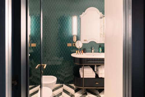 a bathroom with a sink and a toilet and a mirror at The Goethe Hotel - Small Luxury Hotels of the World in Rome