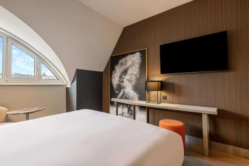 a bedroom with a bed and a tv on a wall at NH Collection Salzburg City in Salzburg