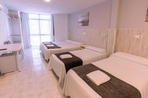 a hotel room with four beds and a desk at Hostal Gran Vía in Pinto