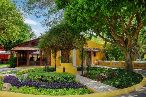 a garden in front of a building with trees and flowers at Hacienda Xcanatun, Angsana Heritage Collection in Mérida