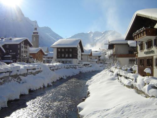 a town with snow covered buildings and a river at Hotel Hartenfels in Lech am Arlberg