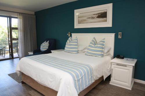 a bedroom with a large bed with blue walls at Blue Lagoon Hotel and Conference Centre in East London