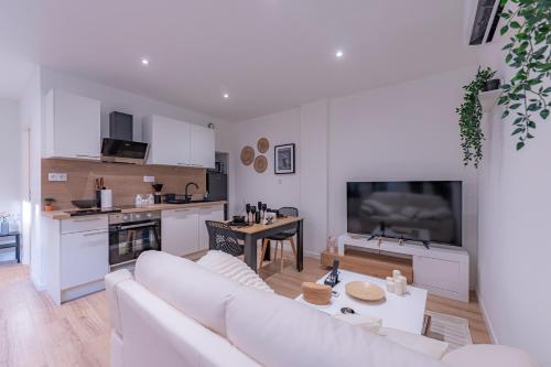 a living room with a white couch and a kitchen at Les Beaux Rêves - A 1h de Lyon in La Côte-Saint-André