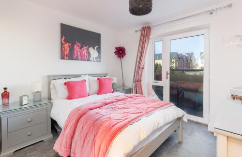 een slaapkamer met een bed met roze kussens en een raam bij Sun Rise in Sandown
