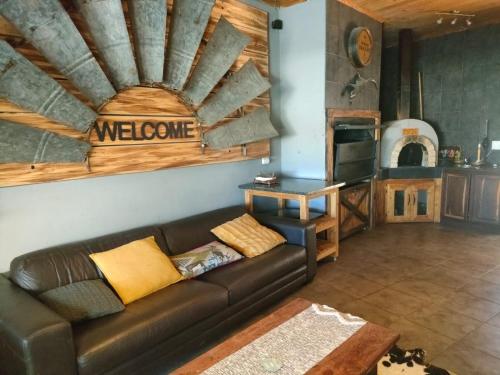 ein Wohnzimmer mit einem braunen Ledersofa und einer Küche in der Unterkunft Leopard Tree Guesthouse in Springbok
