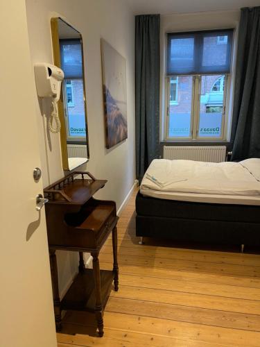 a bedroom with a bed and a table and a mirror at Davaa's Bed & Breakfast in Randers