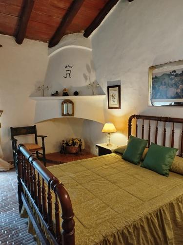 a bedroom with a large bed with green pillows at Hotel Rural El Vaqueril in Navas del Madroño