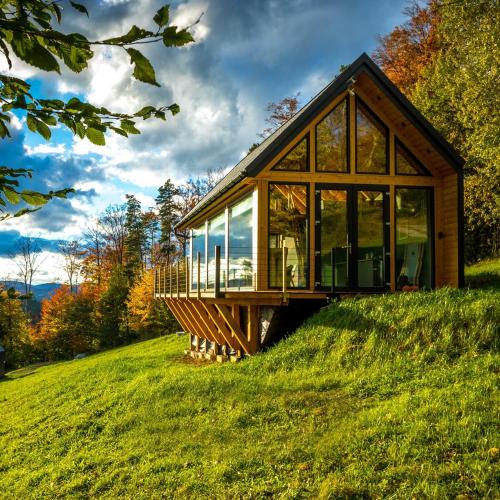 a house on top of a grassy hill at Czas i Las Glamping in Sadek