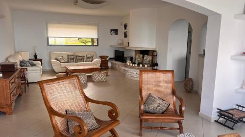 un salon avec deux chaises et un canapé dans l'établissement Villa d exception vue mer panoramique piscine, à Saint-Florent