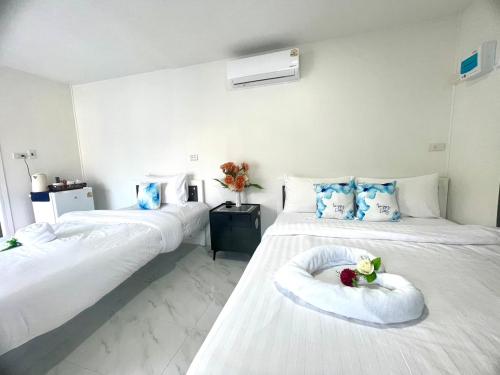 a hotel room with two beds with flowers on them at The White House Pakbara in Ban Pak Ba Ra