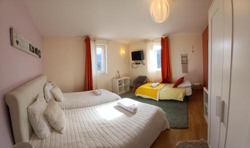 a hotel room with two beds and a television at Les Terrasses du Paradis in Orpierre