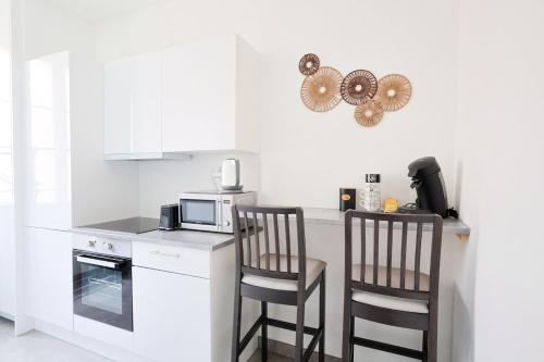 une cuisine blanche avec deux chaises et un micro-ondes dans l'établissement Appartement 2 pieces, à Nice