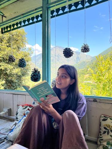 a woman sitting in a window reading a book at The Nook, Sainj in Sainj