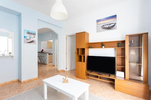 un soggiorno con grande TV e tavolo di Apartamento La Arena Rosa a Candelaria