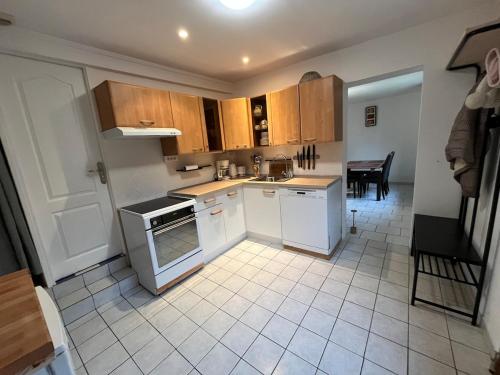 Il comprend une cuisine avec des placards en bois et du carrelage. dans l'établissement Maison au calme au pied du parc Saint Pierre, proche cathédrale, hortillonnages et gare, à Amiens