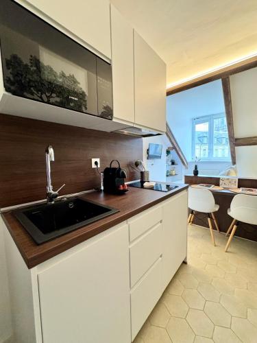 une cuisine avec des armoires blanches et un évier dans l'établissement Le petit Nantais, centre de Rennes, avec vue sur la Cathédrale, à Rennes