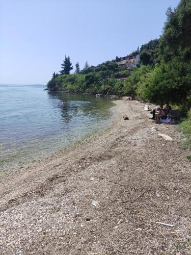 a group of people sitting on a beach near the water at Blue and white apartments 2 in Benitses
