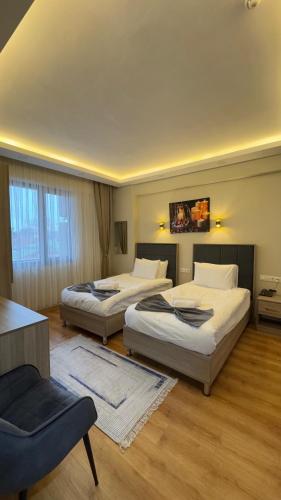 a hotel room with two beds and a chair at Lions Boutique Hotel in Altınova