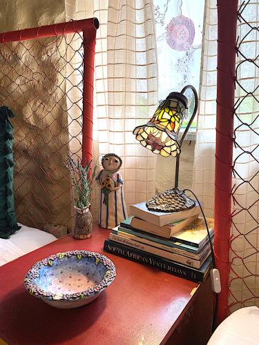 a lamp on a table with books and a plate at ilyn pottery cottage in Pretoria